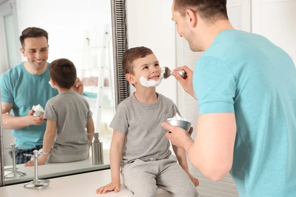 Papá aplicando espuma de afeitar en la cara del hijo en el baño — Foto de Stock