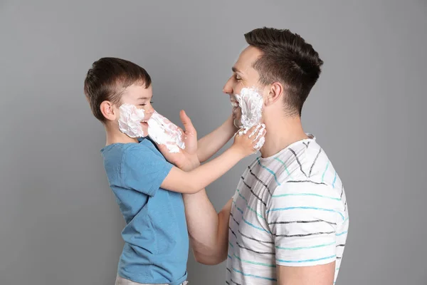 Papa et son petit fils s'amusent en appliquant de la mousse à raser sur fond de couleur — Photo