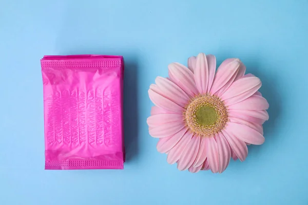 Composição de leigos plana com almofadas menstruais e flor de gerbera no fundo de cor. Cuidados ginecológicos — Fotografia de Stock