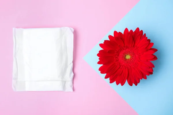 Composición plana con almohadilla menstrual y flor de gerberas sobre fondo de color. Atención ginecológica — Foto de Stock