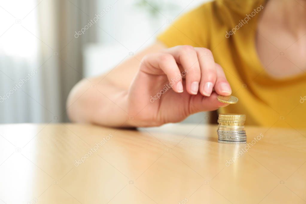 Woman stacking coins on table at home, closeup. Space for text