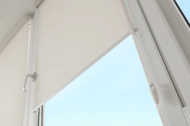 Window with modern roll blinds in room, closeup
