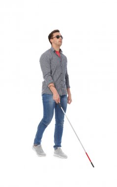 Young blind person with long cane walking on white background