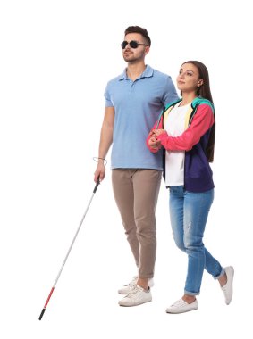 Young woman helping blind person with long cane on white background