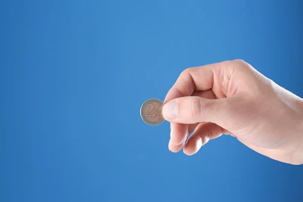 Man holding coin in hand on color background, closeup. Space for text — Stock Photo, Image