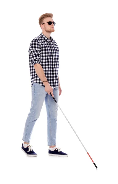 Young blind person with long cane walking on white background — Stok fotoğraf