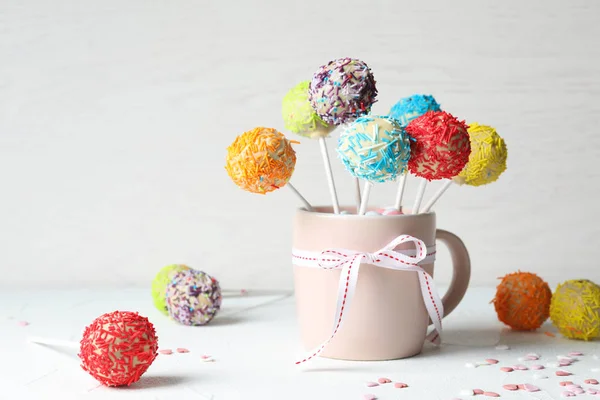 Beker met strik en lekkere kleurrijke cake Pops op tafel. Ruimte voor tekst — Stockfoto
