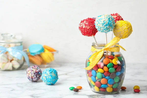 Yummy bright cake pops in glass jar full of candies on table. Space for text — 스톡 사진