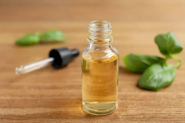 Glass bottle of essential oil on wooden table — Stock Photo, Image