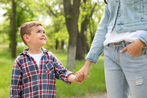 Nettes kleines Kind, das seine Mutter im Freien an der Hand hält. Familienwochenende — Stockfoto