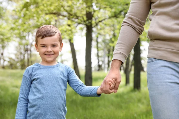 Glückliches kleines Kind hält Händchen mit seinem Vater im Park. Familienzeit — Stockfoto