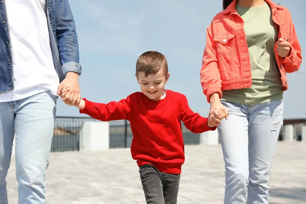 Gelukkig kind houdt de handen met zijn ouders buitenshuis. Familie weekend — Stockfoto