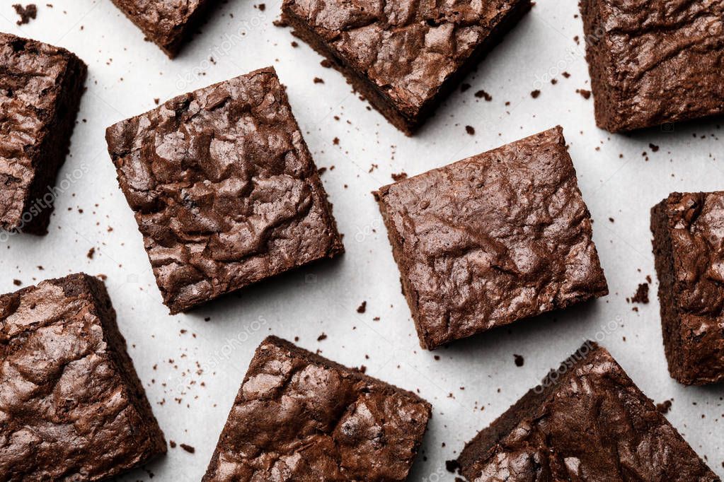 Flat lay composition with fresh brownies on parchment paper. Delicious chocolate pie