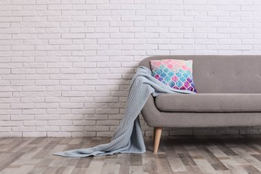 Rahat kanepe, yastık ve tuğla duvara yakın ekose ile Minimalist oturma odası iç. Metin için alan