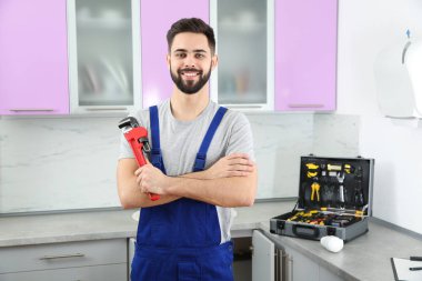 Mutfakta boru anahtarı olan erkek tesisatçı. Onarım hizmeti