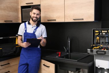 Mutfak lavabosu yakınında pano ile erkek tesisatçı. Onarım hizmeti