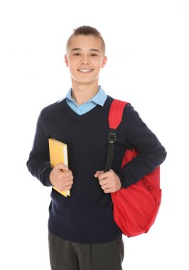 Sırt çantası ve beyaz arka plan kitap ile okul üniforması genç çocuk Portresi