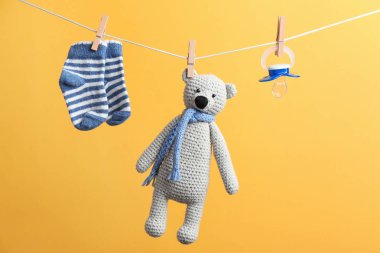 Küçük çorap, emzik ve oyuncak ayı renk arka plan karşı yıkama hattı asılı. Bebek aksesuarları