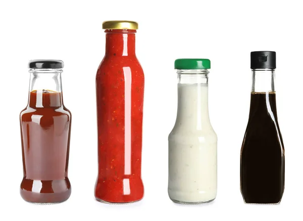 Set de botellas de vidrio con diferentes salsas deliciosas sobre fondo blanco —  Fotos de Stock