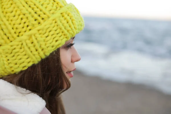 Young woman in warm clothes time near sea