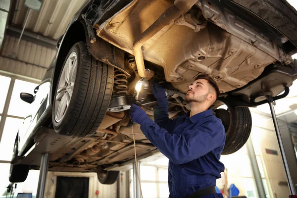 Técnico verificando carro moderno na oficina de reparação de automóveis — Fotografia de Stock