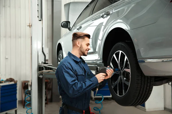Técnico que trabalha com carro na oficina de reparação de automóveis — Fotografia de Stock