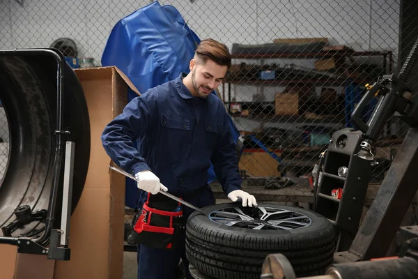 Técnico que trabalha com roda de carro na oficina de reparação automóvel — Fotografia de Stock
