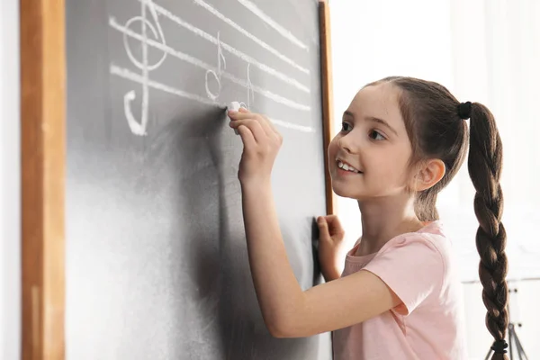 Little Girl írásban zenei jegyzetek táblára az osztályban — Stock Fotó