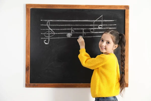 Ragazzina che scrive note musicali sulla lavagna in classe — Foto Stock