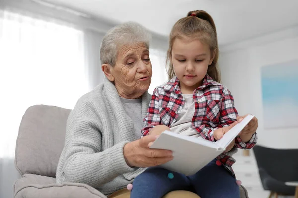 Fille mignonne et sa grand-mère lecture livre à la maison — Photo