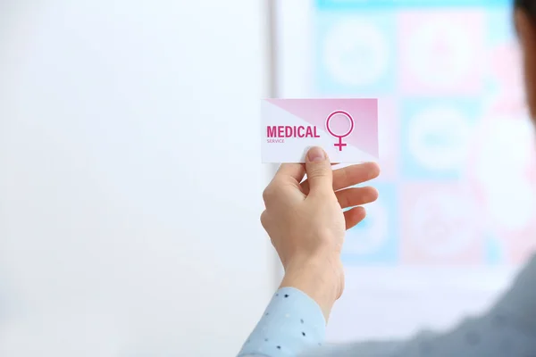 Girl holding medical business card indoors, closeup. Women\'s health service