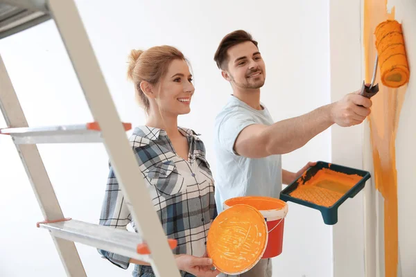 Pareja feliz pintando la pared adentro. Reparación casera —  Fotos de Stock