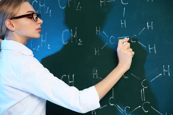 Cientista feminina escrevendo fórmula química em quadro-negro — Fotografia de Stock
