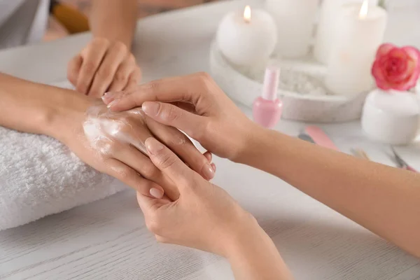 Cosmetólogo aplicación de crema en la mano de la mujer en la mesa en el salón de spa, primer plano —  Fotos de Stock