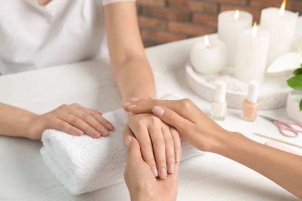 Kosmetikerin massiert Klientin die Hand am Tisch im Wellness-Salon, Nahaufnahme — Stockfoto