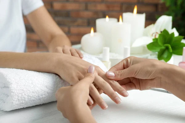 Cosmetólogo masajeando la mano del cliente en la mesa en el salón de spa, primer plano —  Fotos de Stock