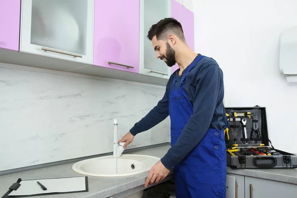Tukang ledeng dengan seragam memeriksa keran di dapur. Perbaiki layanan — Stok Foto