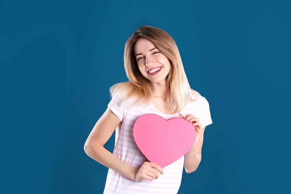 Portret van mooie vrouw met hartvormige Gift Box op kleur achtergrond — Stockfoto