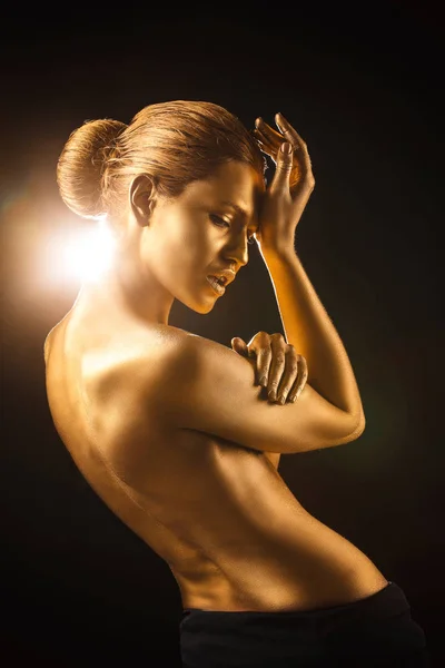 Retrato de bela senhora com tinta dourada na pele contra fundo preto — Fotografia de Stock