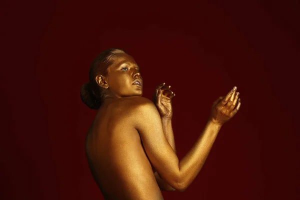 Retrato de bela senhora com tinta dourada na pele contra fundo de cor — Fotografia de Stock