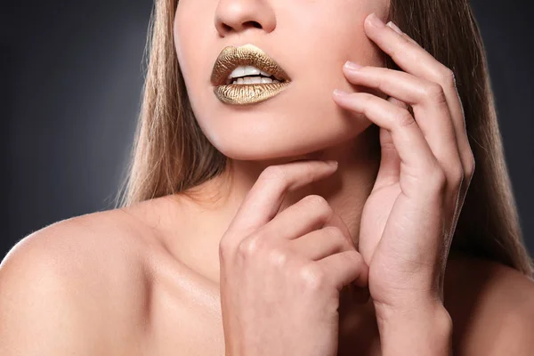 Mujer con lápiz labial dorado sobre fondo gris, primer plano — Foto de Stock