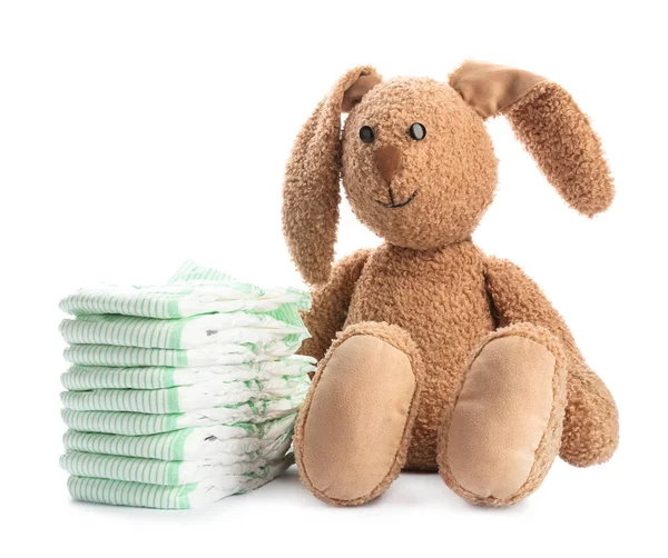 Pilha de fraldas e coelho de brinquedo no fundo branco. Acessórios para bebés — Fotografia de Stock