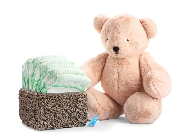 Basket with diapers, pacifier and teddy bear on white background. Baby accessories — Stock Photo, Image