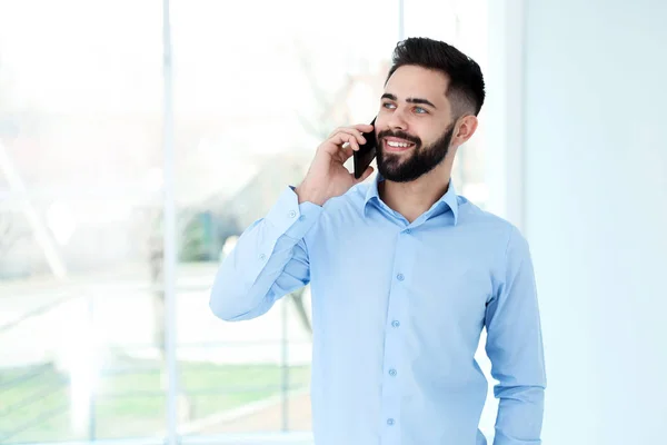 Knappe jonge man praat met de klant via de telefoon op het werk. Ruimte voor tekst — Stockfoto