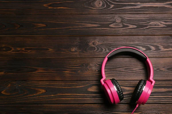 Auriculares elegantes sobre fondo de madera, vista superior. Espacio para texto — Foto de Stock