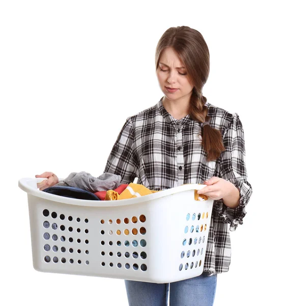 Mujer joven disgustada sosteniendo cesta con lavandería sobre fondo blanco — Foto de Stock
