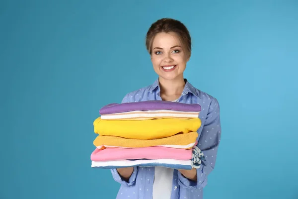 Счастливая молодая женщина держит чистое белье на цветном фоне — стоковое фото