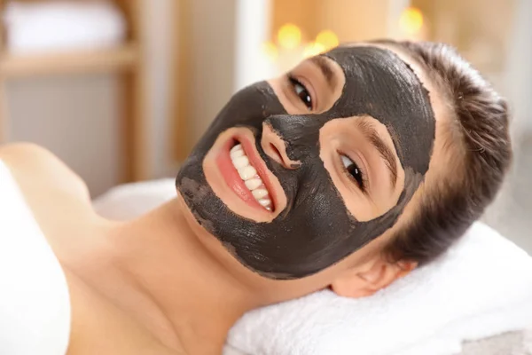 Krásná žena s černou maskou na obličeji relaxační v lázeňském salonu — Stock fotografie