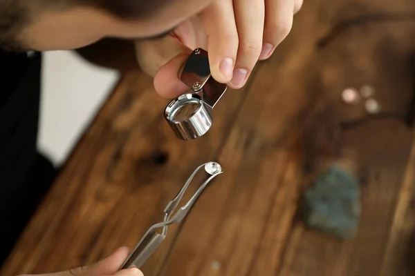 Mannelijke juwelier evalueren van kostbare edelstenen aan tafel in workshop, close-up — Stockfoto