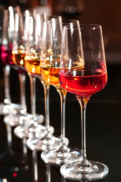 Fila di calici con diversi vini in tavola sullo sfondo sfocato — Foto Stock